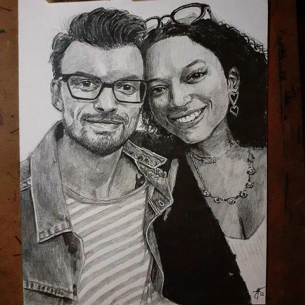 a smiling couple side by side, the man in glasses and a denim jacket, the woman in a striped top